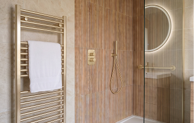 A warm-toned, fully level-access bathroom with grab rails and a wood vanity.